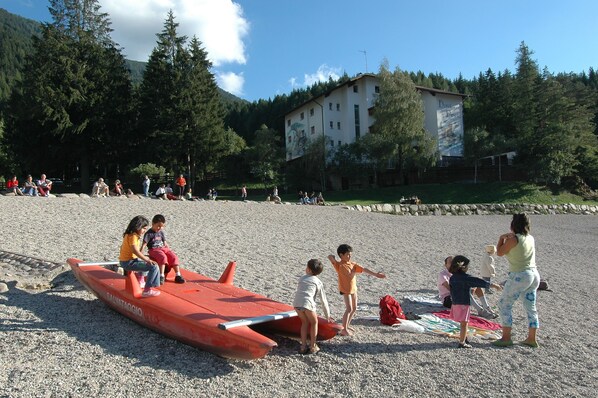A beach with a lifeguard tower, people sitting and standing, and a building in the background.