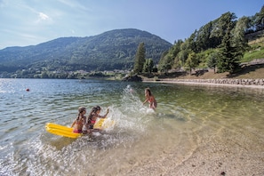 A lake with clear water, surrounded by mountains and trees.