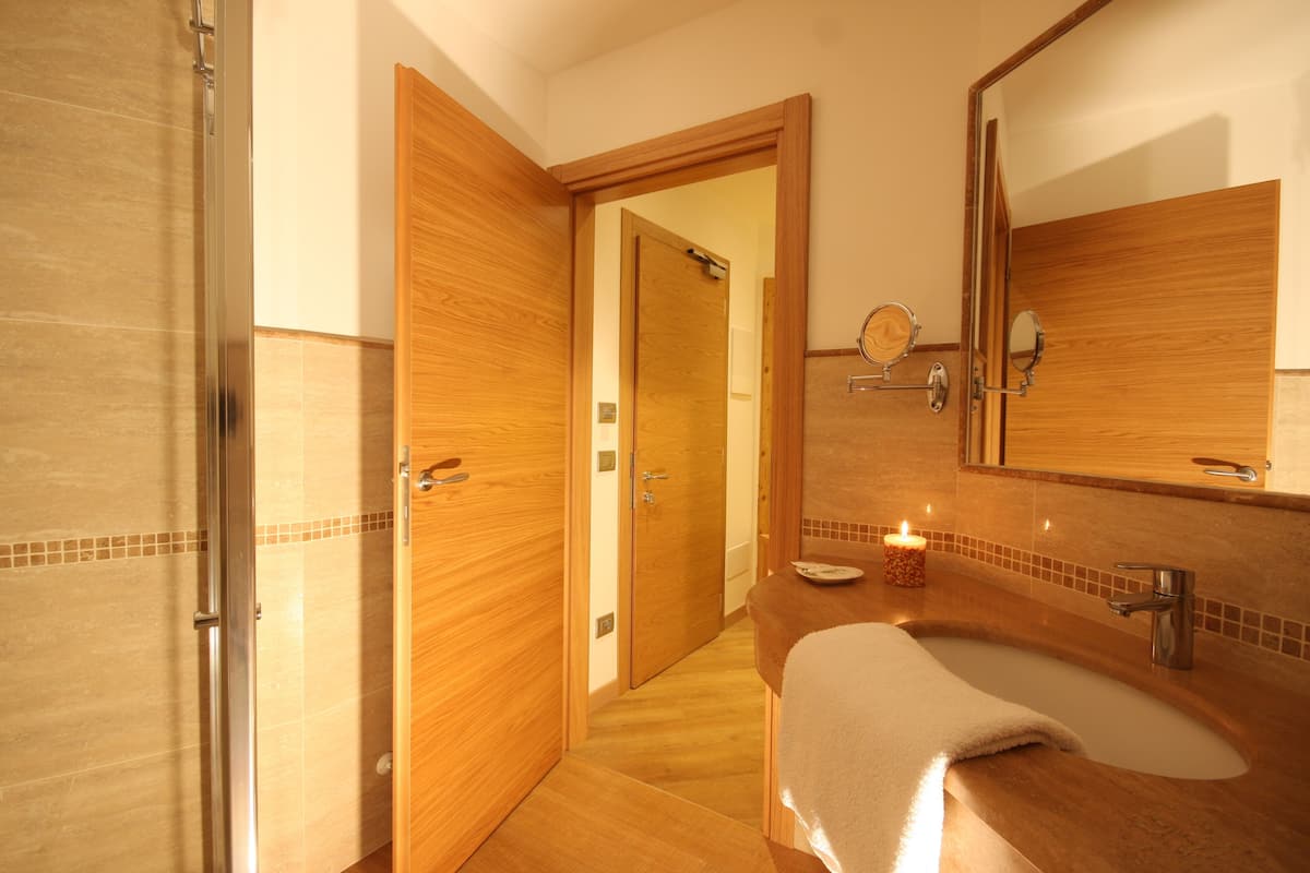 Ein Badezimmer mit einem Holzbadschrank, einem Waschbecken, einem Spiegel und einer Dusche.