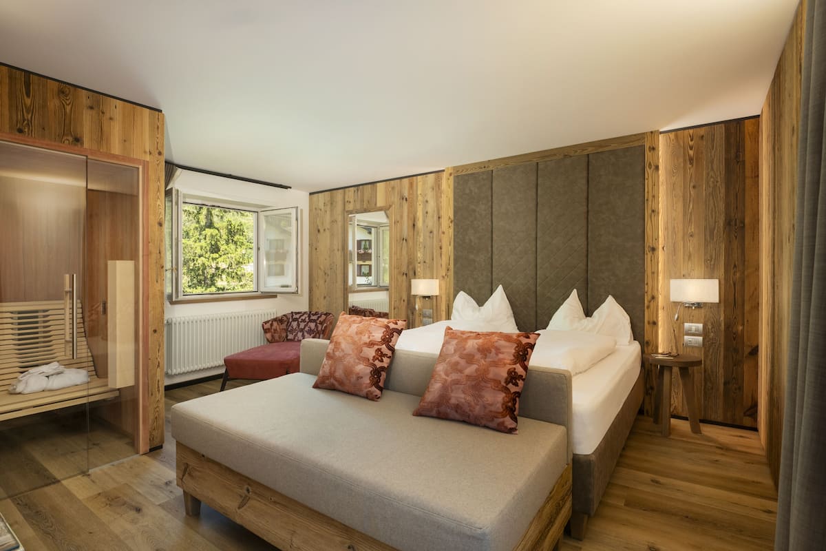 Ein modernes Schlafzimmer mit Holzboden, einem großen Bett mit zwei Kissen, einem Nachttisch mit Lampe und einem Kleiderschrank.