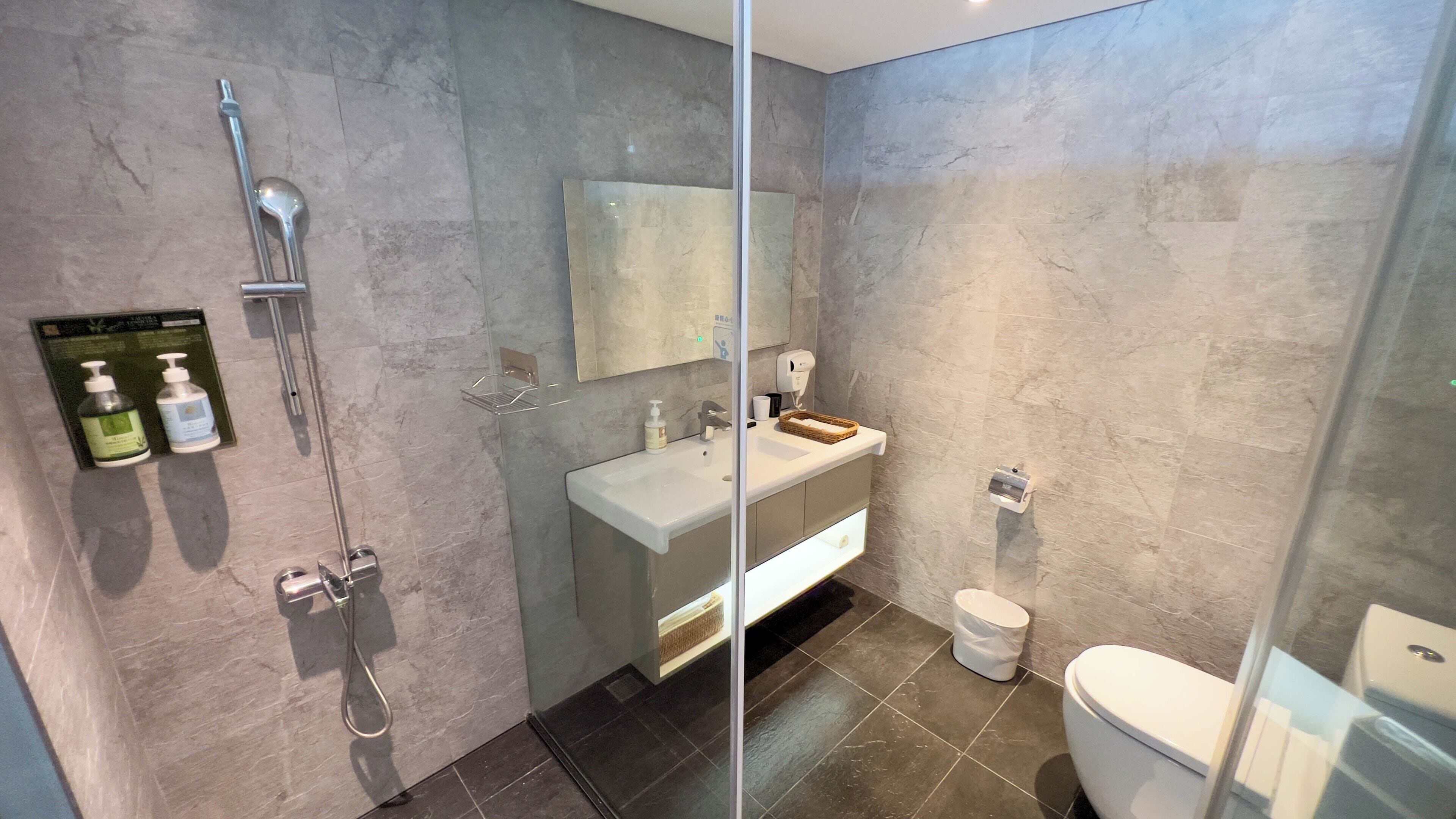 Un baño moderno con cabina de ducha de vidrio, tocador con espejo y retrete.