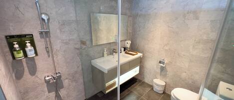 Un baño moderno con cabina de ducha de vidrio, tocador con espejo y retrete.