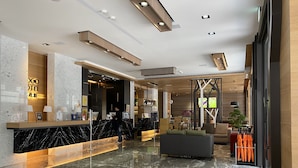 A modern hotel lobby with a marble reception desk, a seating area, and a large window. - GOGO HOTEL 38 (Taichung)