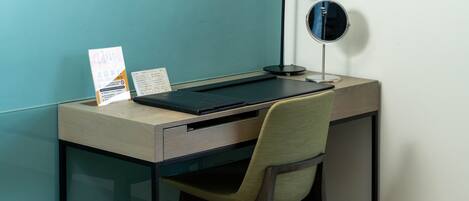 A desk with a laptop, a lamp, a mirror, and a chair.