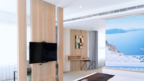 A modern hotel room with a large bed, a flat-screen TV mounted on a wooden panel, a view of the sea, and a balcony with a railing. - GOGO HOTEL 38 (Taichung)