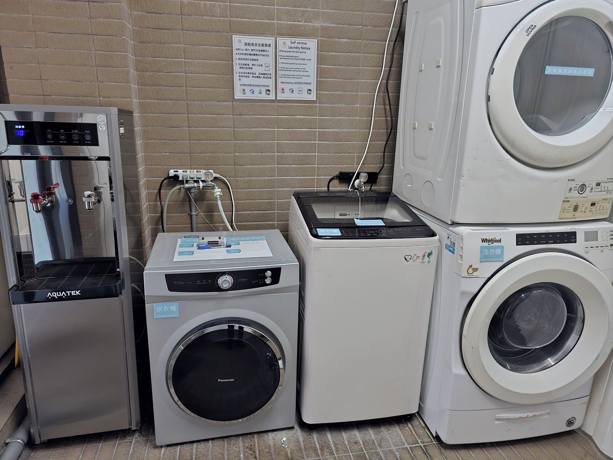 Un área de lavandería con una secadora Panasonic, una lavadora Whirlpool y un enfriador de agua Aquatek.