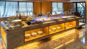 A buffet setup with a marble counter, various food items, and a seating area with chairs. - GOGO HOTEL 38 (Taichung)