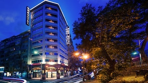 A multi-story hotel with a prominent sign, a well-lit entrance, and a street view with light trails. - Silken Hotel (Taipei)