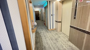 A hotel corridor with a carpeted floor, wooden paneling, and a sign indicating an exit. - Silken Hotel (Taipei)
