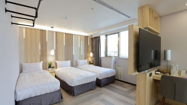 A hotel room with two beds, a desk, a TV, and a window with curtains. - Silken Hotel (Taipei)