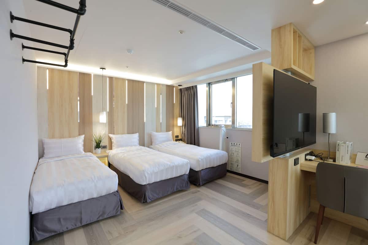 Une chambre d’hôtel avec deux lits, un bureau, une télévision et une fenêtre avec des rideaux.