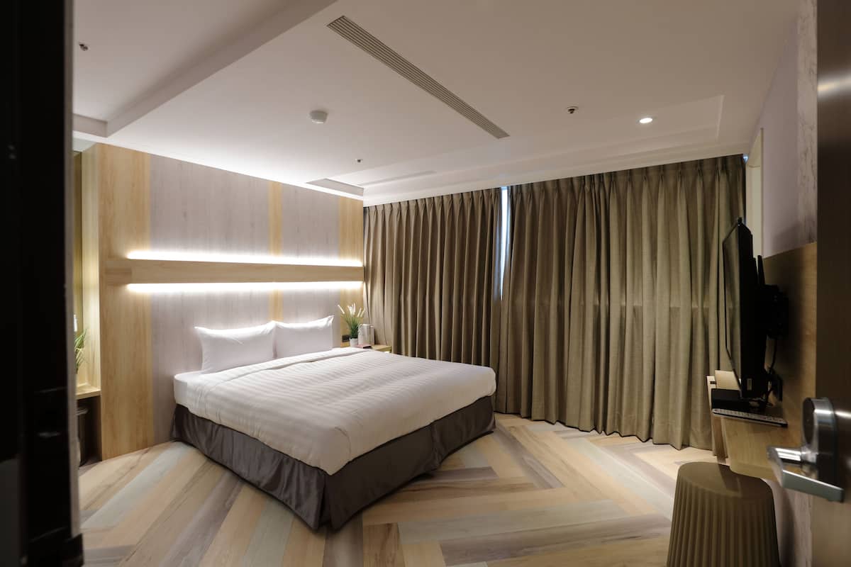 Une chambre d’hôtel moderne, dotée d’un grand lit, d’un bureau et d’une télévision.
