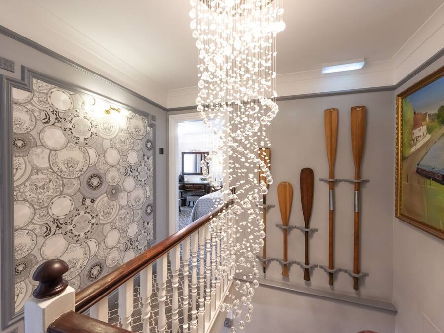 A staircase with a patterned wall, wooden paddles, and a painting.