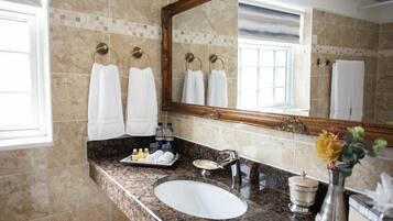 A bathroom with a marble sink, a large mirror, and multiple white towels hanging on towel rings.