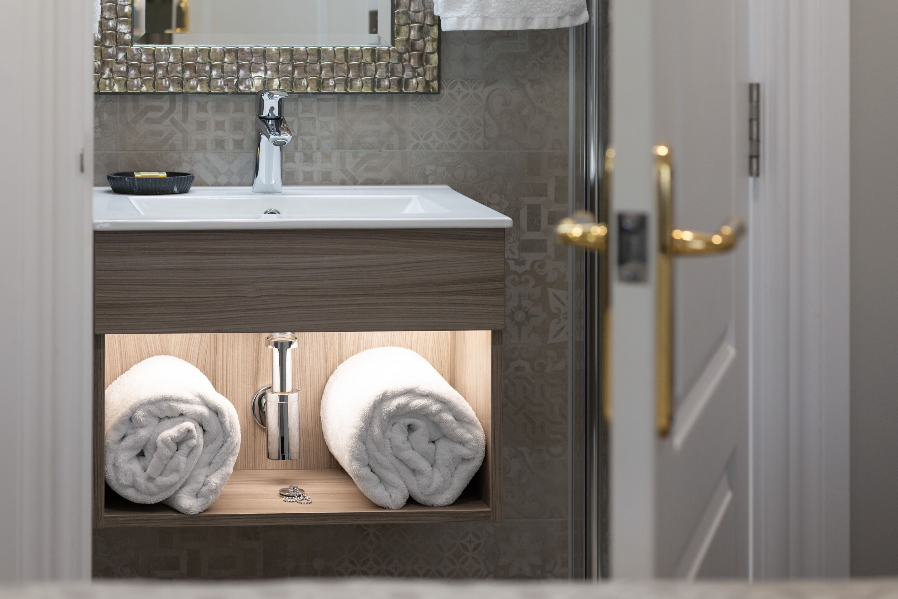 A bathroom with a sink, mirror, and towel storage.