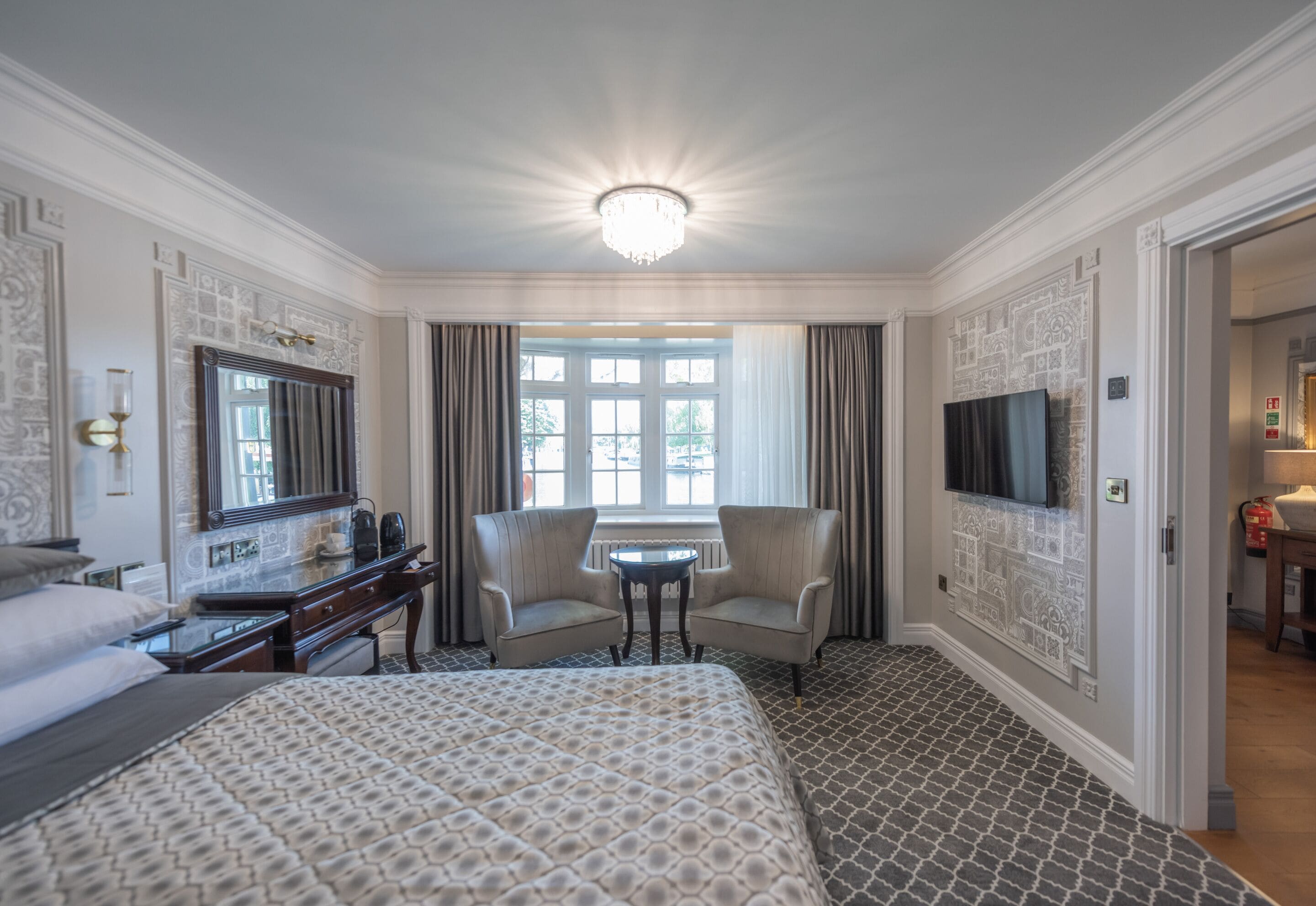 Een hotelkamer met een groot bed, een bureau met stoel, een televisie en een raam met gordijnen.