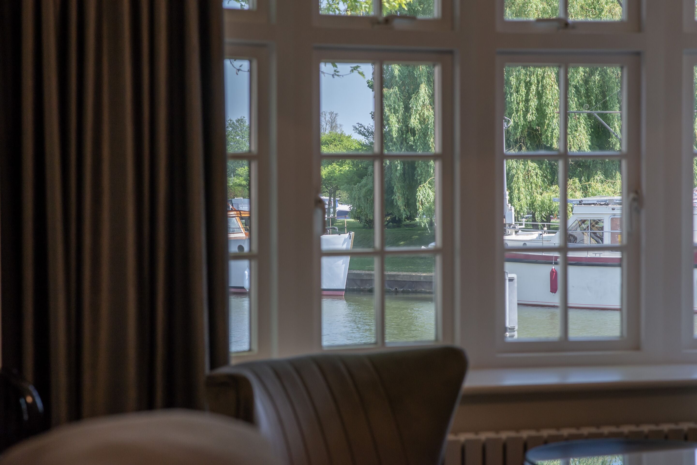A room with a view of a canal through a window, a chair, and a radiator.