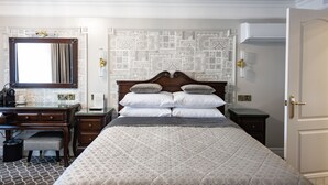 Um quarto bem arrumado com uma cama grande, uma escrivaninha de madeira e um espelho.
