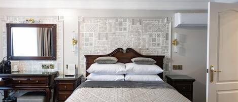 Um quarto bem arrumado com uma cama grande, uma escrivaninha de madeira e um espelho.
