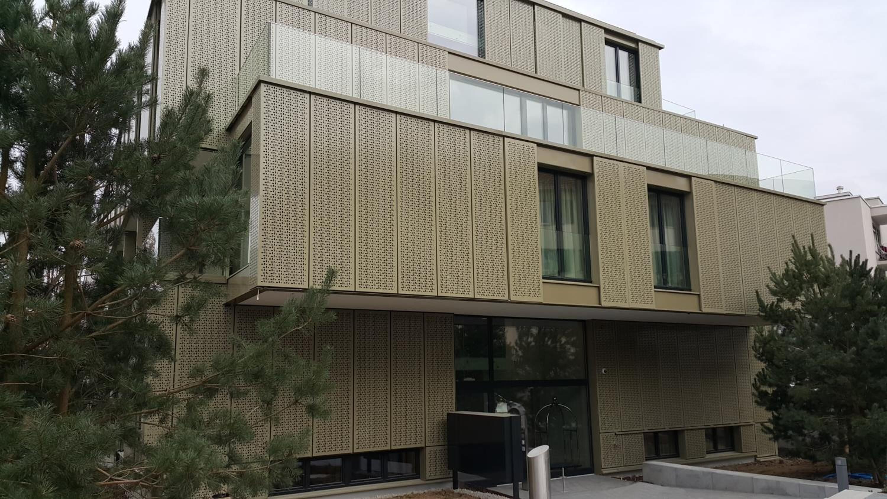 Un edificio moderno con fachada texturizada, ventanas grandes y techo plano.