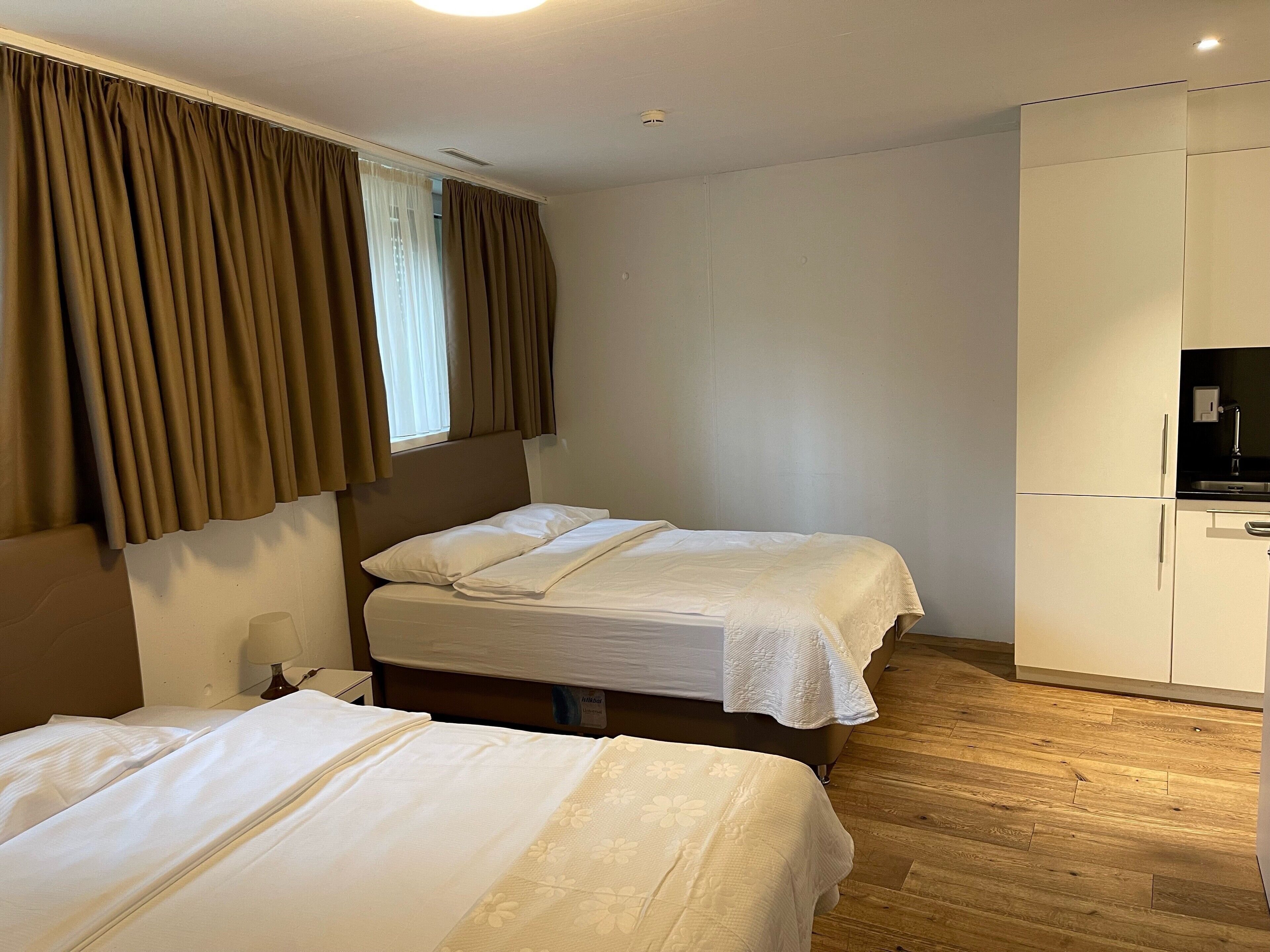 Camera d'albergo con due letti, un armadio e una televisione.