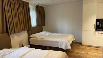 A hotel room with two beds, a wardrobe, and a television.
