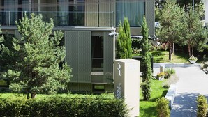 Een modern gebouw met meerdere balkons, een verzorgde tuin en een heldere lucht.