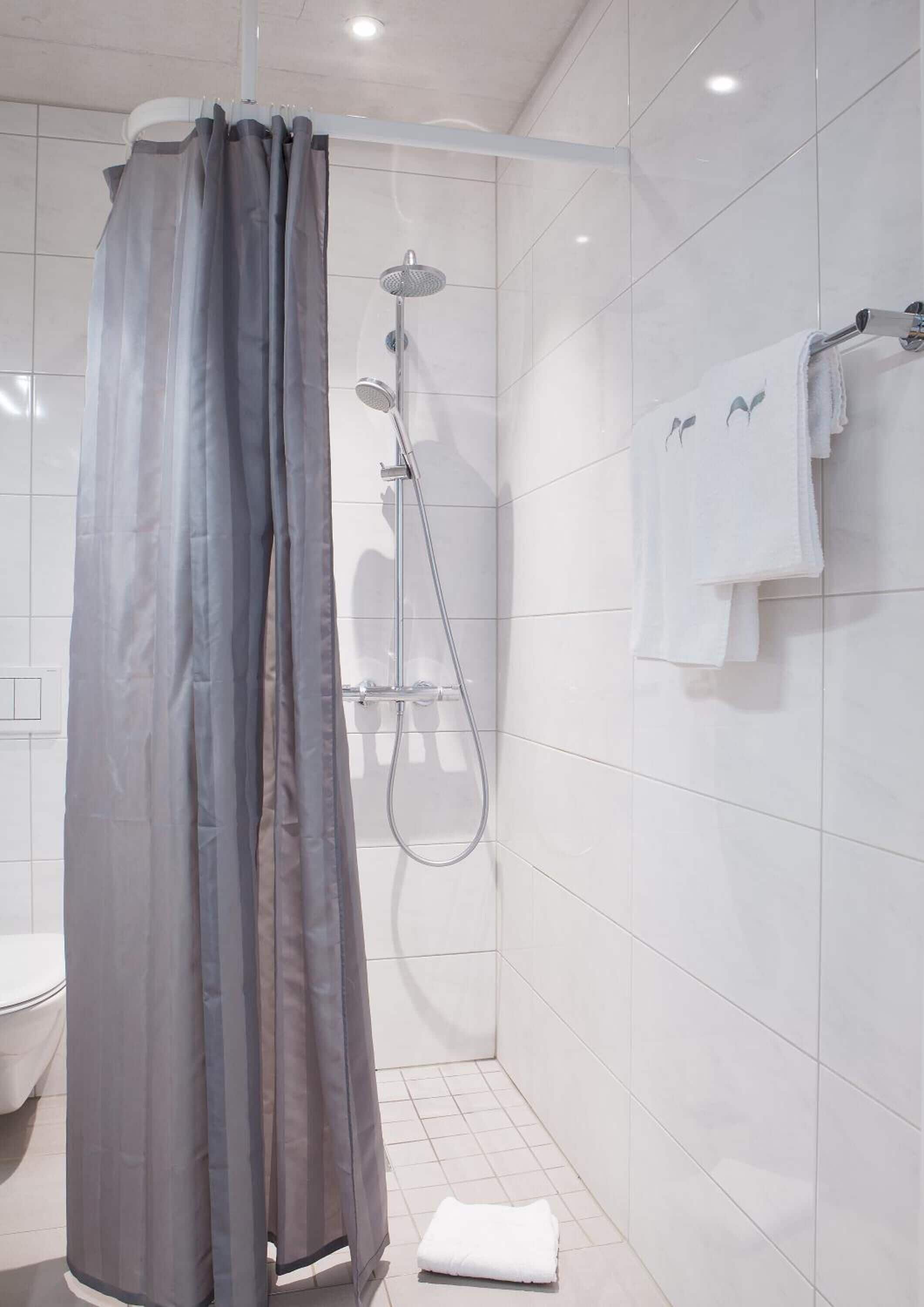 Moderni kylpyhuone, jossa on suihku, wc ja pyyheteline.