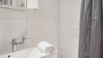 A modern bathroom with a white sink, mirror, and toilet.