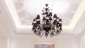 A room with a black chandelier, two upholstered chairs, a glass table, and a checkered floor. - Lafayette Boutique Hotel Yogyakarta (Depok)