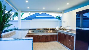 A modern kitchen with granite countertops, stainless steel appliances, and wooden cabinets. - Tulip House Pool Villa Hua Hin (Cha-am)
