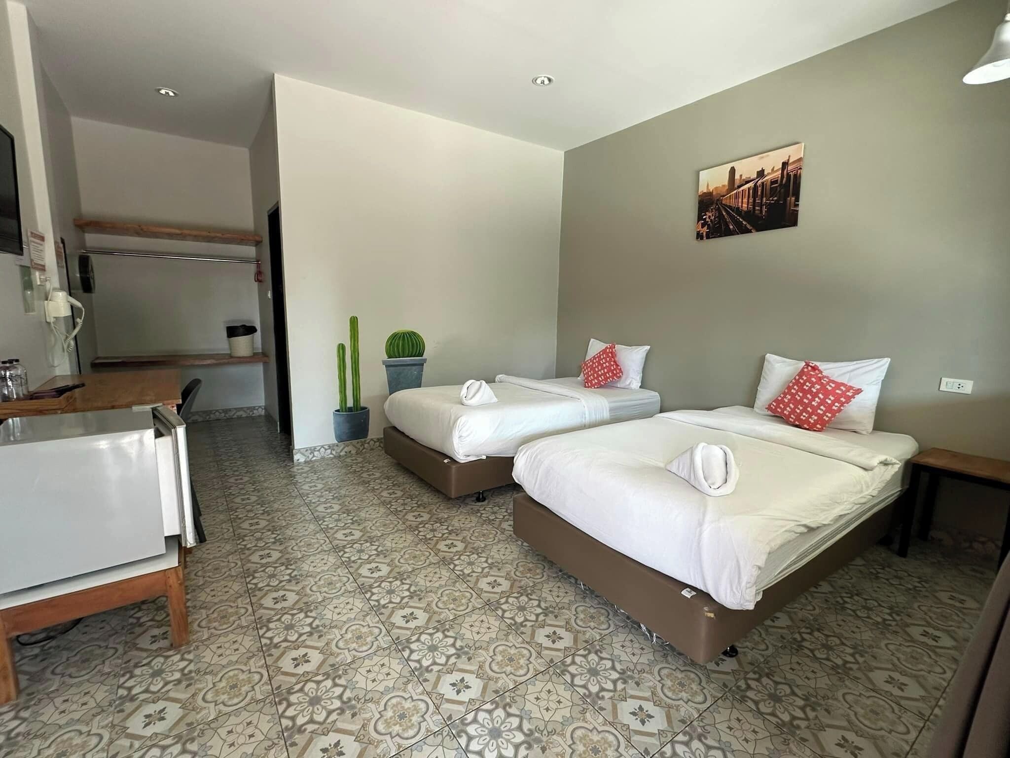 Una habitación de hotel con dos camas, un escritorio y una pequeña cocina.