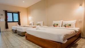 Une chambre d’hôtel avec un grand lit, deux petits lits et une fenêtre avec des rideaux.
