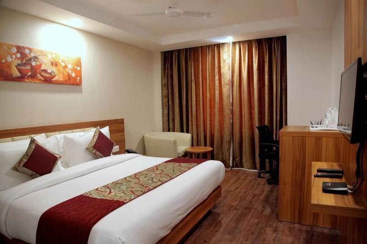 A hotel room with a bed, a TV, a desk, and a chair.