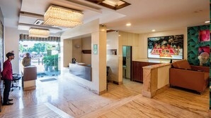 A hotel lobby with a reception desk, a seating area, and a kitchen. - Le Roi Jammu (Jammu)