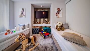 Une chambre d’enfant avec deux lits, un cheval à bascule, une voiture jouet et un ours en peluche.