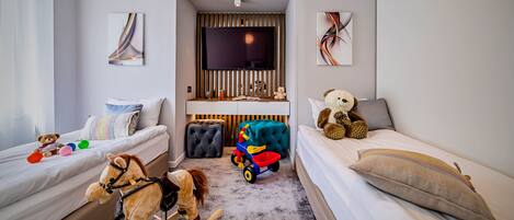A child's bedroom with two beds, a rocking horse, a toy car, and a teddy bear.