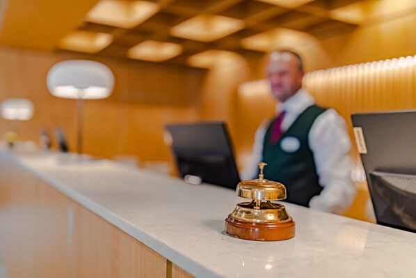 Un mostrador de recepción de hotel con un timbre, una barra y una estación de registro.