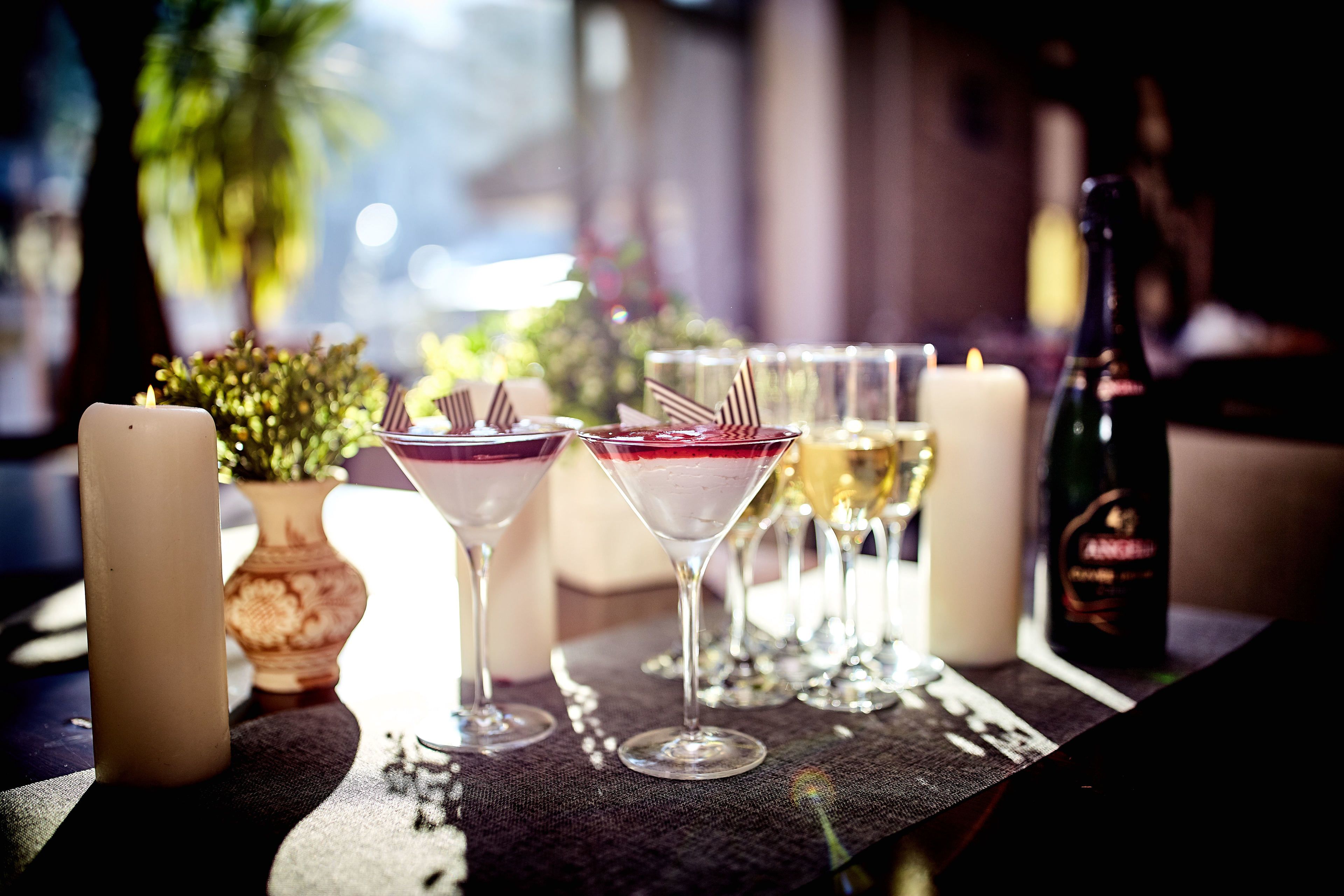 Et bord med to martini-glas, et stearinlys og en champagneflaske.