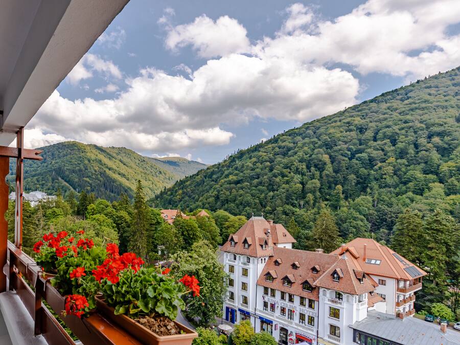 A hotel with a traditional European architectural style, featuring multiple stories and a prominent balcony with red flowers.
