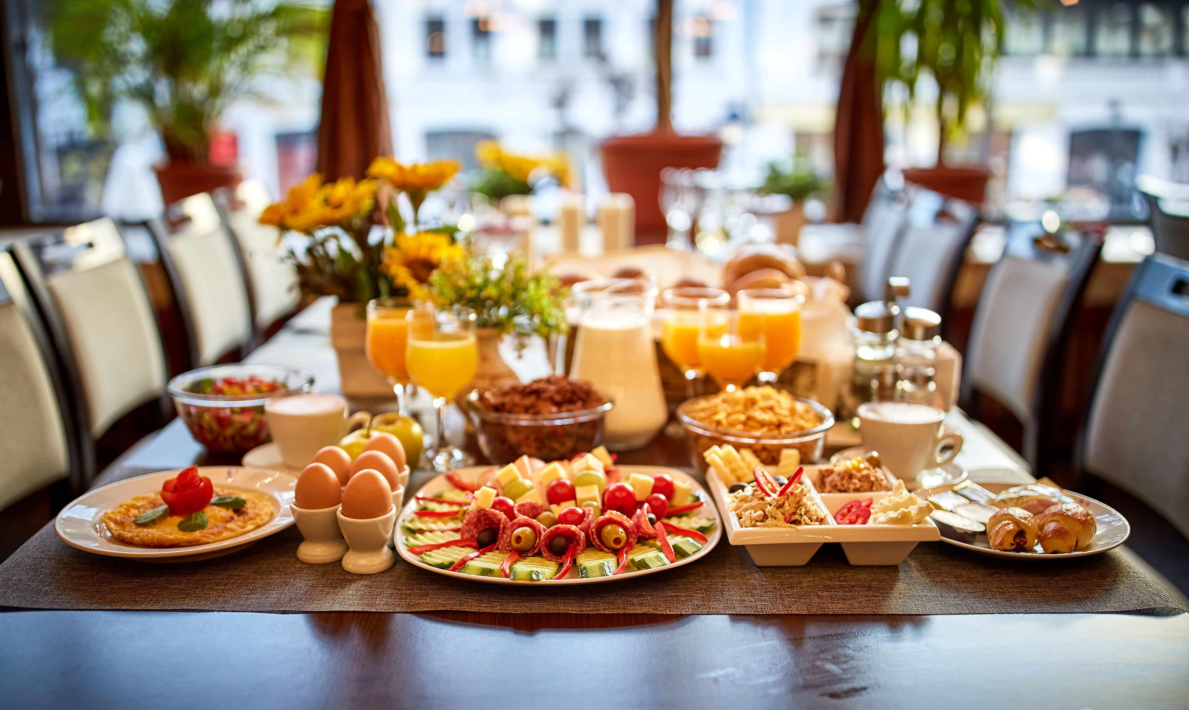 A breakfast buffet with various dishes, drinks, and a view of the city.