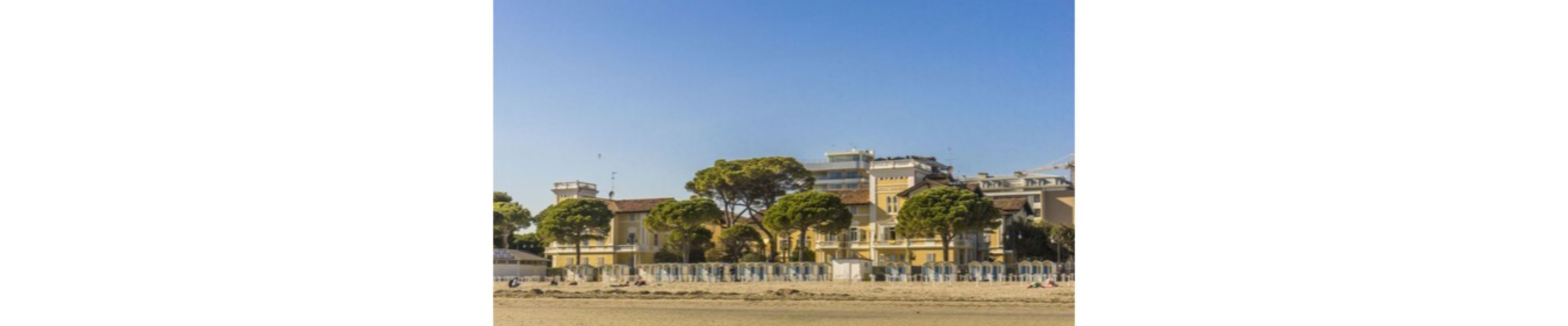 Un edificio costero con varios balcones y una playa arenosa al frente.