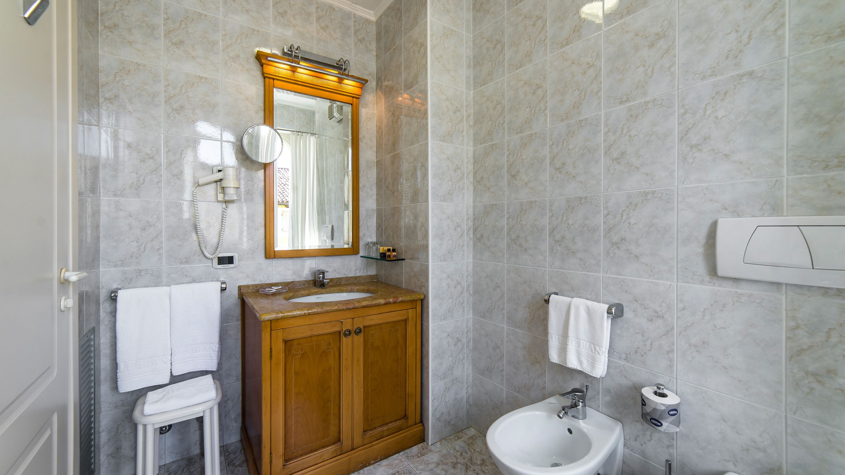 A bathroom with a wooden vanity, a sink, a mirror, a towel rack, and a toilet paper holder.