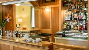Una zona de bar con mostrador, estación de café y estantería con botellas de licor.