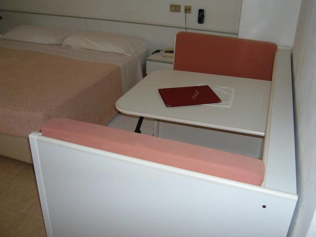 A small, single-bed room with a bedside table and a red book on it.