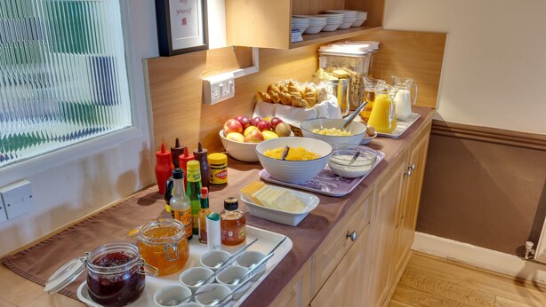 Ein Frühstücksbuffet mit verschiedenen Speisen, Gewürzen und Getränken.