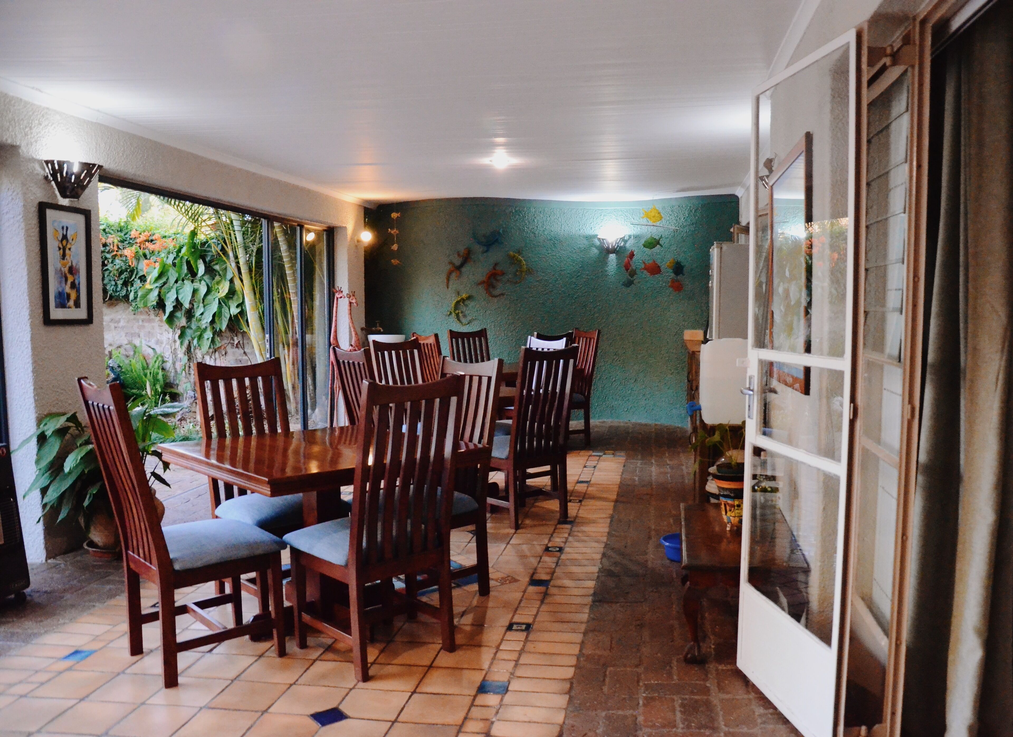 A dining area with a tiled floor, wooden chairs, a table, and a wall decorated with fish and plants.