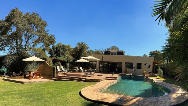 A modern house with a swimming pool, outdoor seating, and lush greenery. - Malcolm Lodge (Harare)