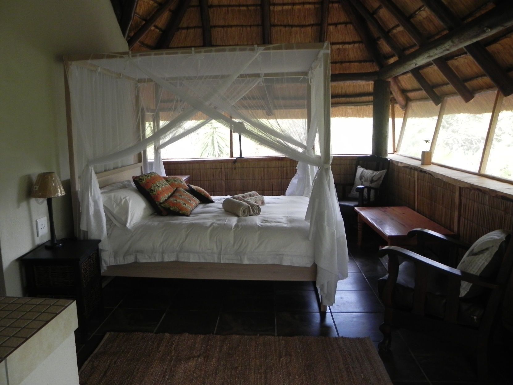 Een kamer met een bed onder een hemelbed, een bureau en een stoel.