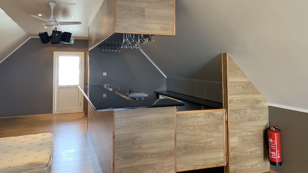 Een moderne keuken met houten kastjes, een zwart aanrecht en een plafondventilator.